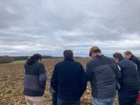 Dans un champ, un groupe de 5 personnes regardent un document